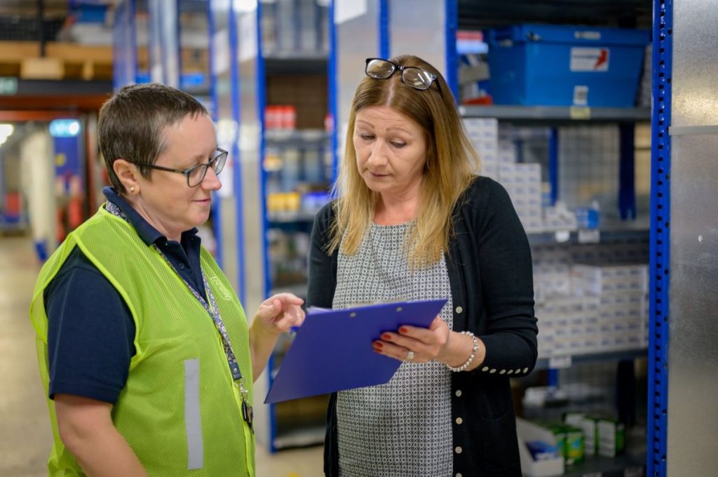 Two people reviewing an inspection checklist in a warehouse aisle
